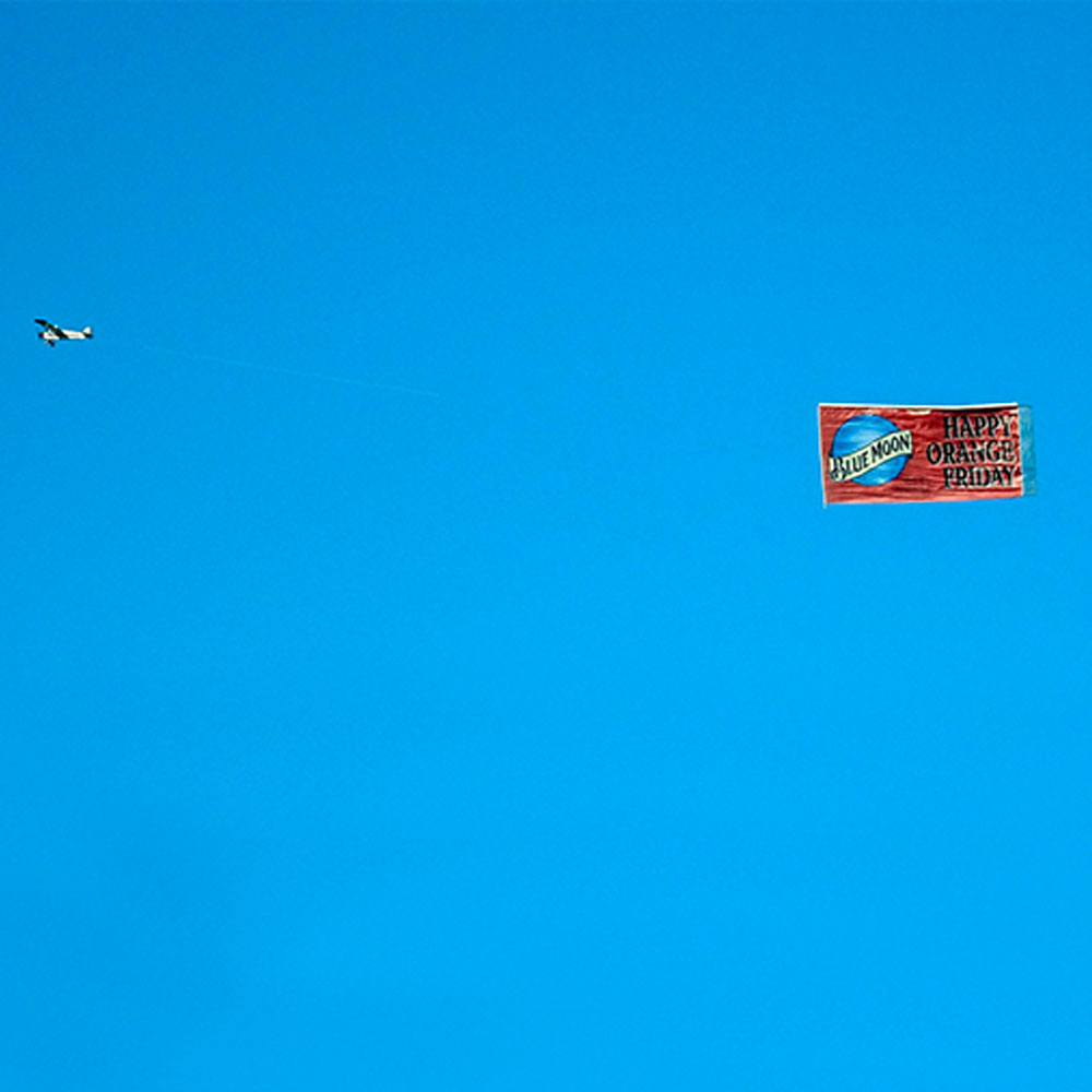Airplane pulling an advertising flight banner across a blue sky